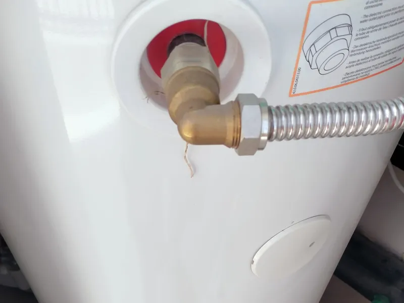 Conexiones hidráulicas de un Ariston Nuos con la etiqueta que recuerda montar el manguito dieléctrico