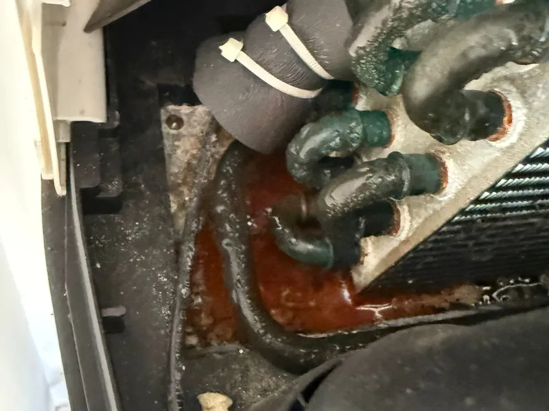 Parte frigorífica de una bomba de calor con tubos corroídos y restos de óxido por condensados mal evacuados