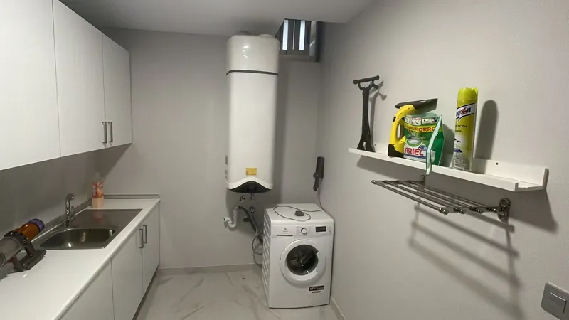 Lavadero con una bomba de calor Ariston Nuos instalada en la pared junto a la lavadora