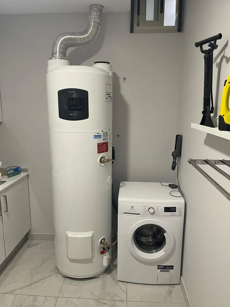 Bomba de calor para agua caliente Ariston NUOS Plus instalada en un lavadero, con conducto de aire al exterior