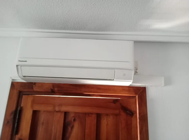 Unidad interior de aire acondicionado split Panasonic instalada sobre una puerta de madera